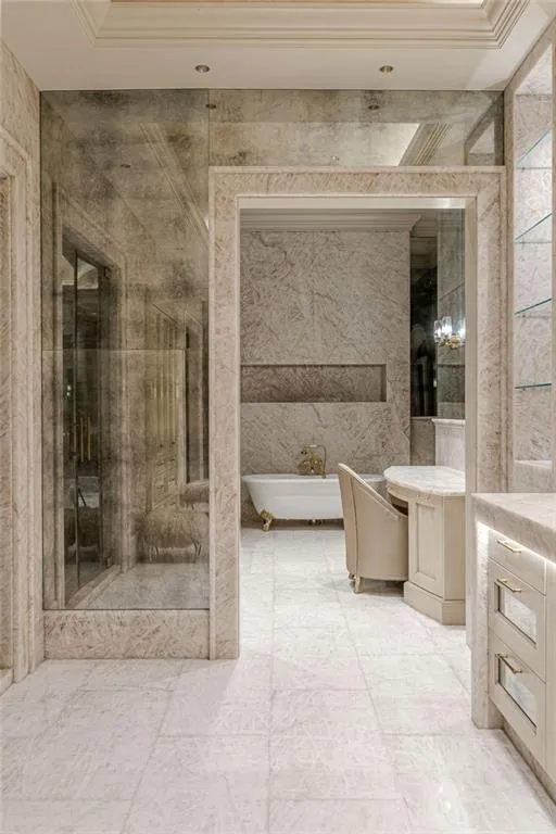 Full bath featuring vanity, a soaking tub, tile walls, and a marble finish shower