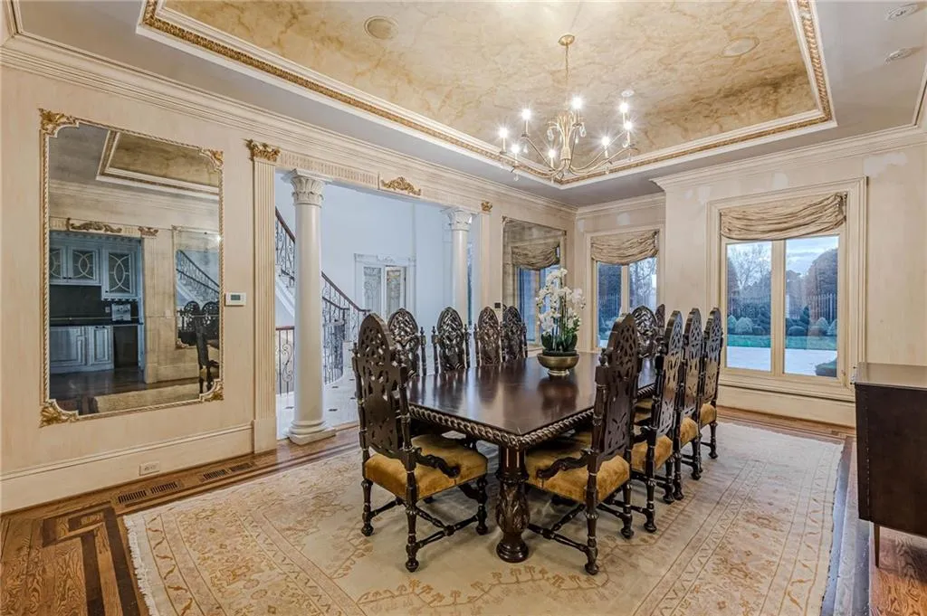 Dining space with decorative columns, ornamental molding, a chandelier, a raised ceiling, and hardwood / wood-style floors