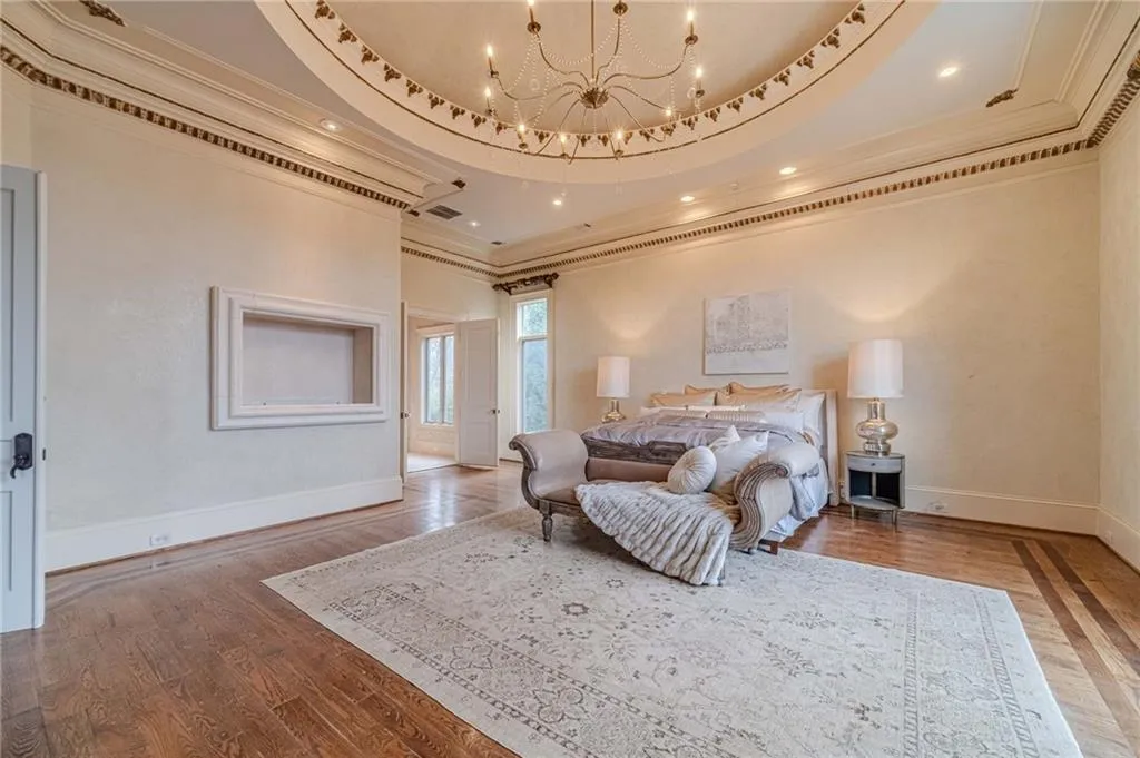 Bedroom with a chandelier, a raised ceiling, ornamental molding, light wood-style floors, and recessed lighting