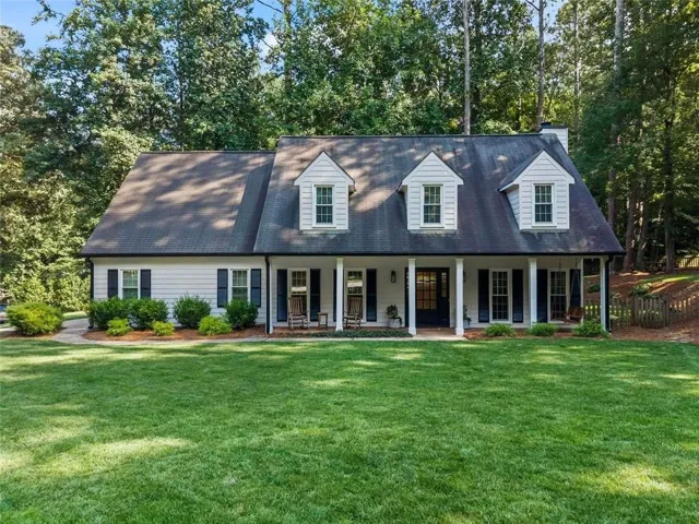 Traditional-style residence featuring a prominent front porch with white columns, three dormer windows, and dark shutters