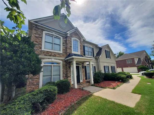 Two-story residence featuring a stone and stucco exterior, multiple gabled rooflines, and a covered entry porch