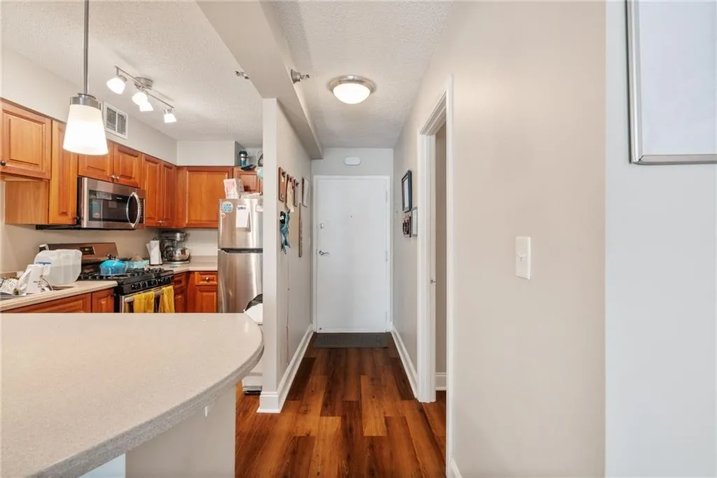 Kitchen featuring hanging light fixtures, rail lighting, wood-type flooring, appliances with stainless steel finishes, and a textured ceiling