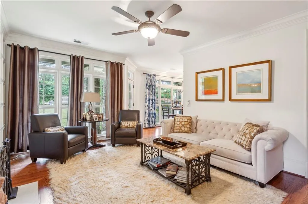 Living room featuring crown molding, light wood-style floors, and ceiling fan