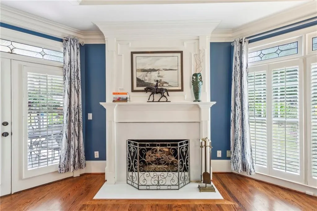 Living area with wood finished floors, ornamental molding, and a fireplace with flush hearth