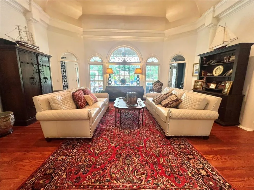 Sitting room with dark wood-style flooring, a high ceiling, and crown molding