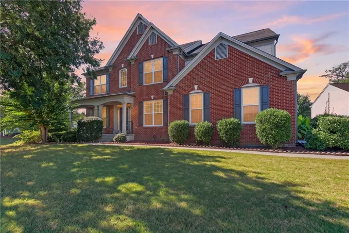 Brick exterior with multiple gables, covered porch, established lawn, and mature landscaping