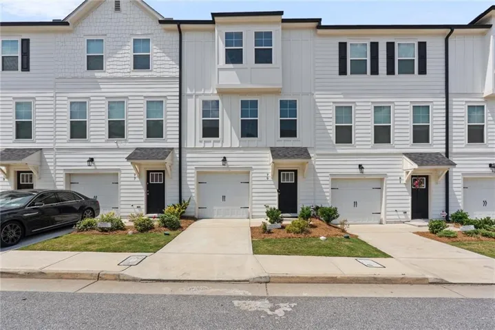 Contemporary townhome facade featuring white siding and black trim accents