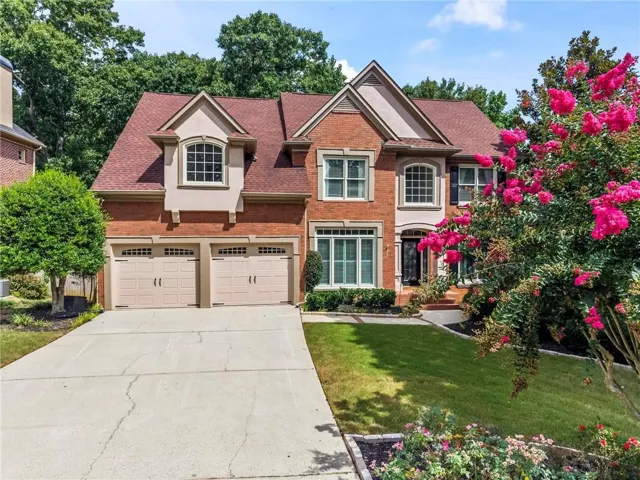 Brick facade residence featuring a prominent two-car garage with carriage-style doors