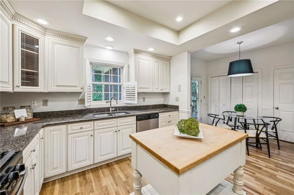Kitchen with hanging light fixtures, light wood-style floors, stainless steel appliances, glass insert cabinets, and recessed lighting