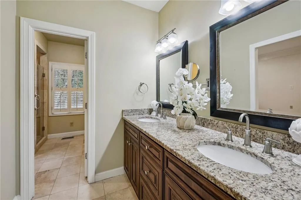 Full bathroom featuring light tile patterned floors, double vanity, and a stall shower