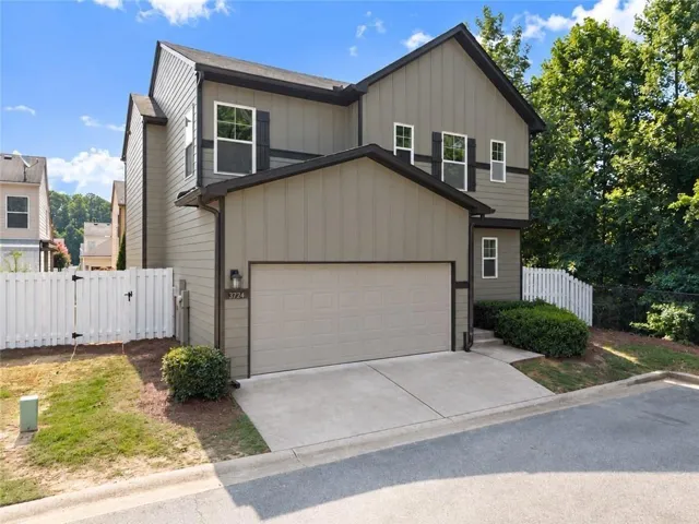 Contemporary exterior with board and batten siding, attached garage, concrete driveway, and white picket fencing