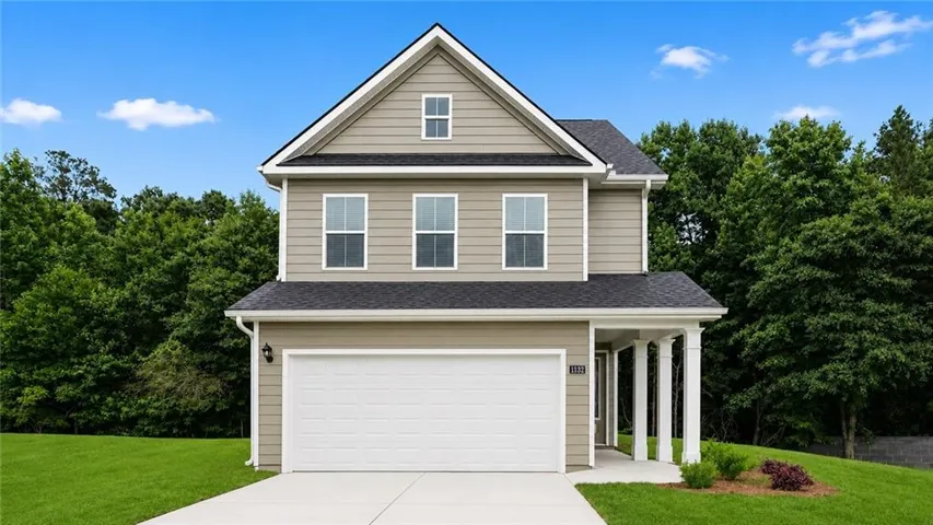Two-story residence featuring light brown siding and a dark shingle roof