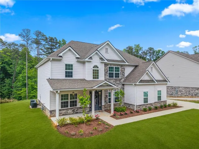 Two-story residence featuring white siding and stone accents