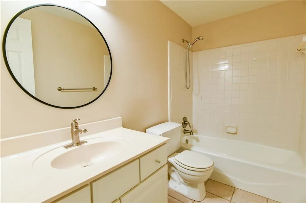 Full bathroom featuring tiled shower / bath combo, vanity, toilet, and tile patterned flooring