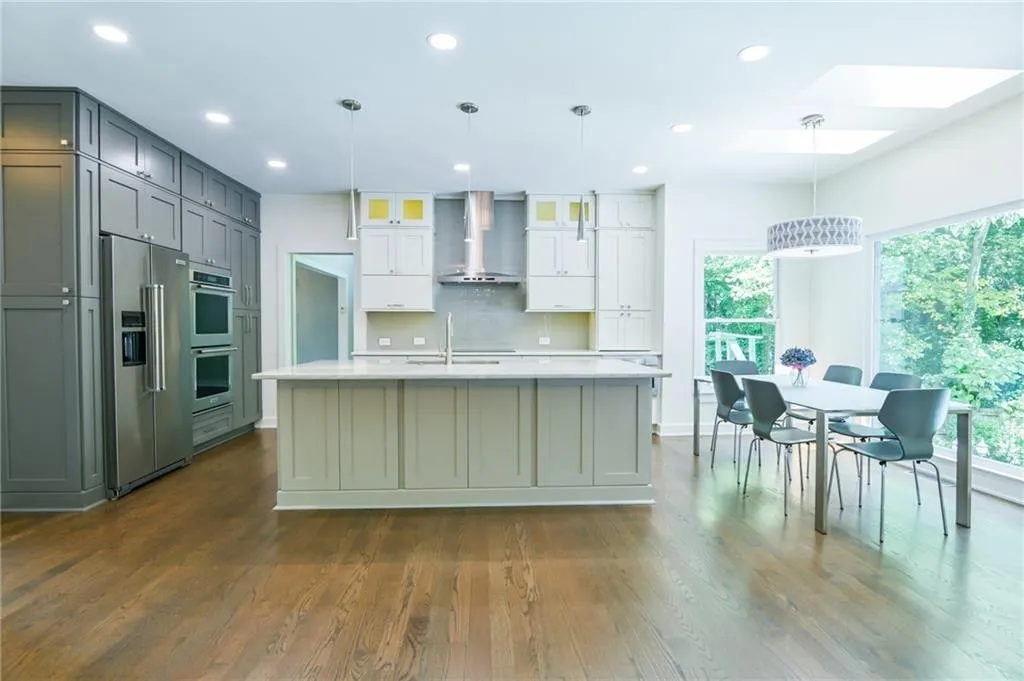 Kitchen featuring wall chimney exhaust hood, plenty of natural light, a skylight, and appliances with stainless steel finishes