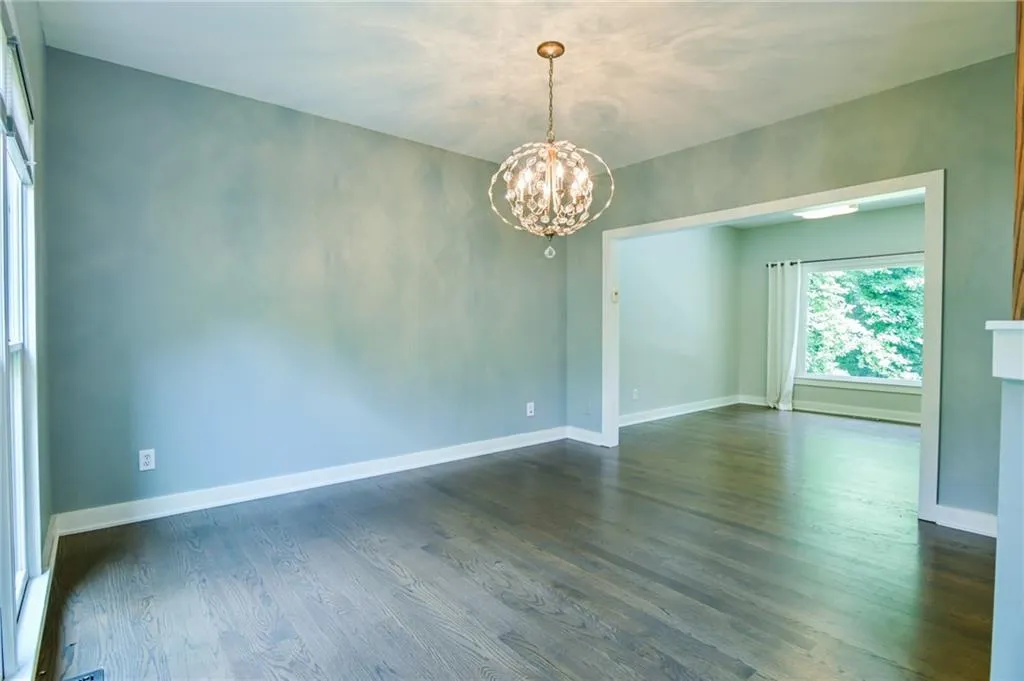 Empty room featuring an inviting chandelier and dark hardwood / wood-style flooring