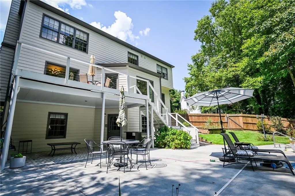 Rear view of house with a balcony, a patio area, and a yard