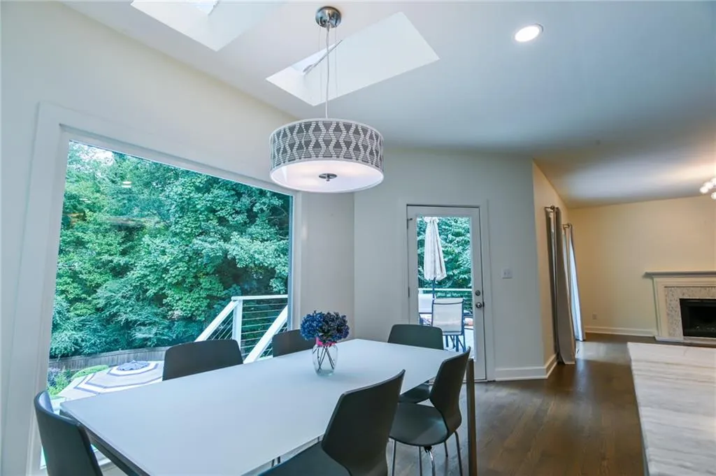 Dining area with a high end fireplace, dark wood-type flooring, and a skylight