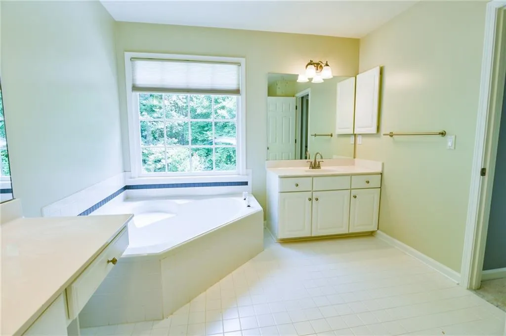 Bathroom featuring vanity, a relaxing tiled tub, and tile patterned floors