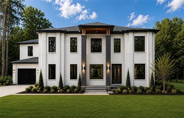 Contemporary two-story residence featuring a white brick facade and black trim windows