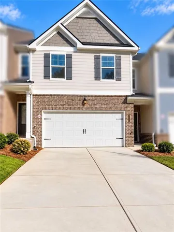 Exterior featuring a two-story design with brick and siding, a white garage door, and a concrete driveway
