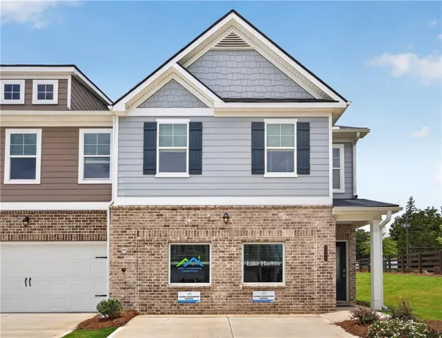 Two-story townhouse exterior featuring a brick facade on the first level and light blue siding on the second