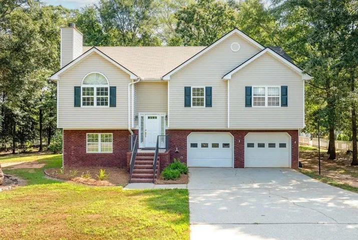 Split-level residence featuring a brick and siding exterior, two-car garage, and a concrete driveway