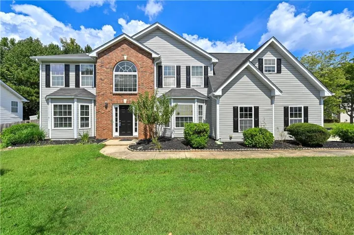 Two-story exterior featuring a brick facade, light gray siding, a prominent arched window, a covered entry, and black window shutters