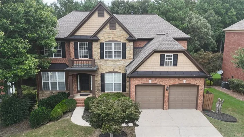 Brick and stone exterior with architectural shingles, two-car garage, and a covered entryway