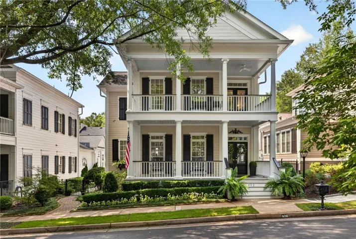 Two-story exterior with columned porches, black louvered shutters, mature trees, and sidewalks