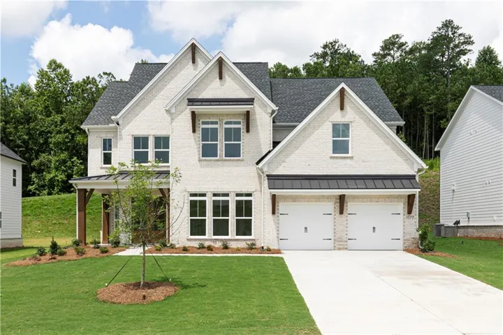 Brick exterior with dark gray roofing, a covered porch with timber columns, a two-car garage, and a concrete driveway