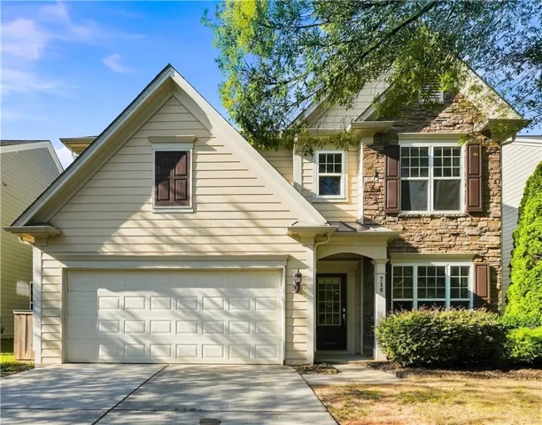 Two-story residence featuring a stone and siding facade, an attached two-car garage, and a covered entry