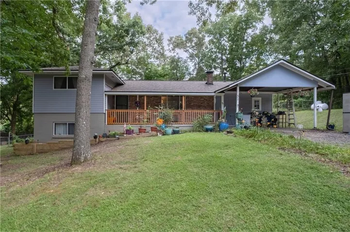 Split-level residence featuring gray siding and a covered front porch with a wood railing