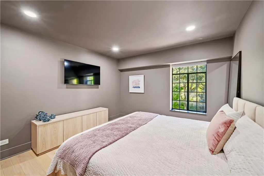Neutral-toned walls featuring recessed lighting, a multi-pane grid window with a dark frame, and light wood-finish cabinetry