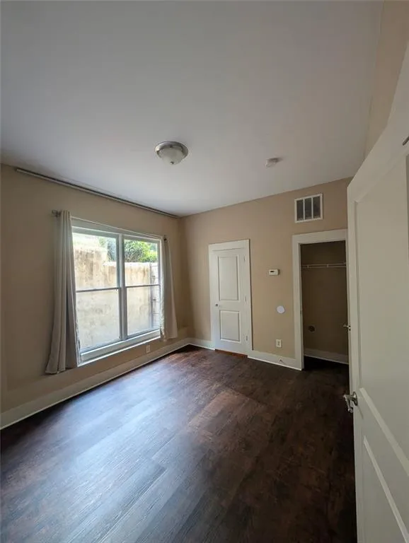 Spare room with dark wood-style flooring and baseboards