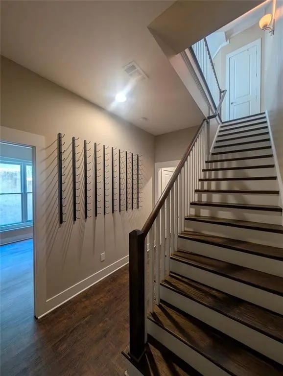 Stairway with wood finished floors and baseboards