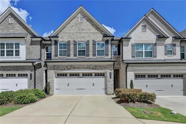 Brick exterior with white garage doors, dark shutters, and gabled rooflines