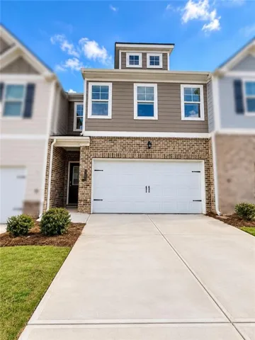 Brick and siding exterior with a dormer, featuring a white garage door with decorative hardware