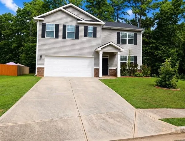 Two-story residence featuring light gray siding, black shutters, and a covered entryway