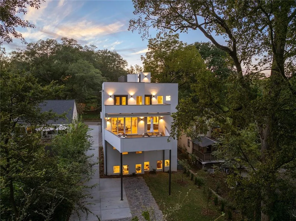 Rear view of house with a balcony, stucco siding, driveway, and a lawn