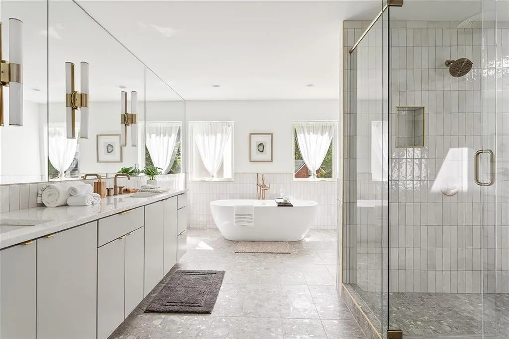 Full bathroom with tile walls, a freestanding bath, a stall shower, double vanity, and a wainscoted wall