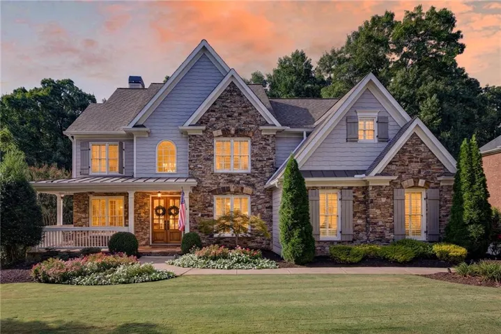 Stone and siding exterior with gabled roof lines, covered front porch, double entry doors, and established landscaping