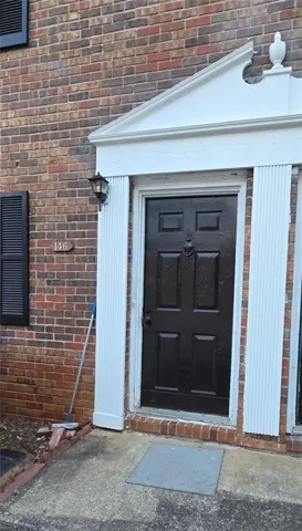 Brick exterior with decorative white door surround and black panel door