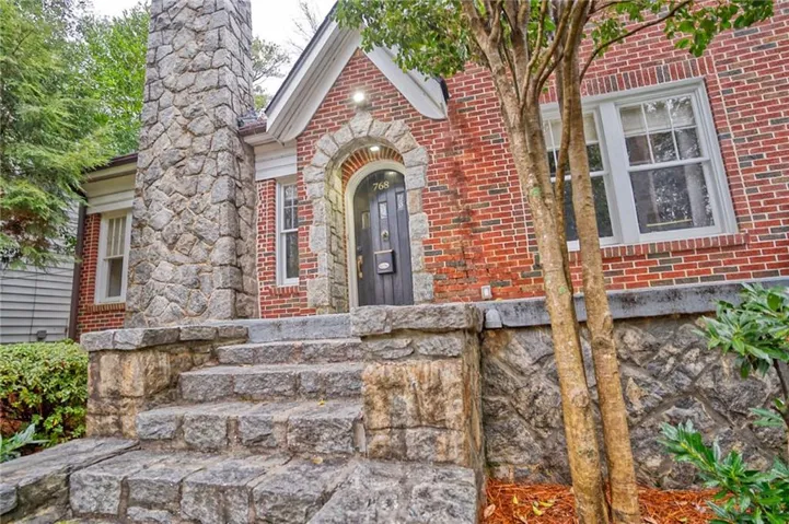Brick and stone facade featuring a prominent stone chimney and stone entry steps