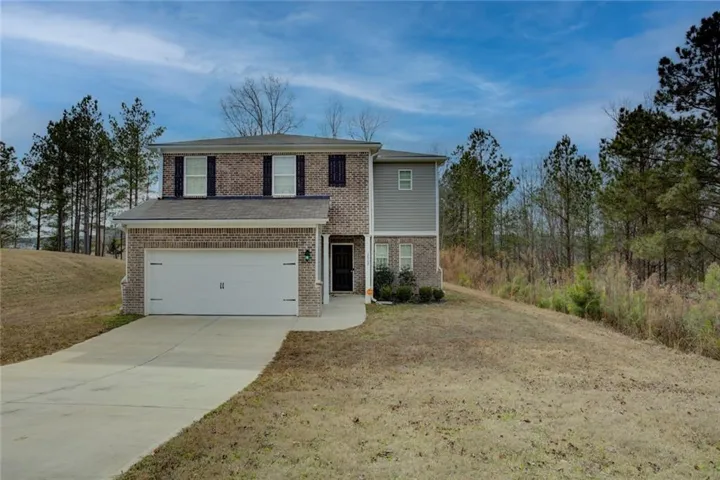 Traditional-style house with an attached garage, driveway, brick siding, and a front lawn