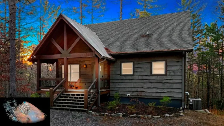 Wood-sided cabin exterior with a covered porch, exposed wood beams, metal accent roof, and dark shingle roofing