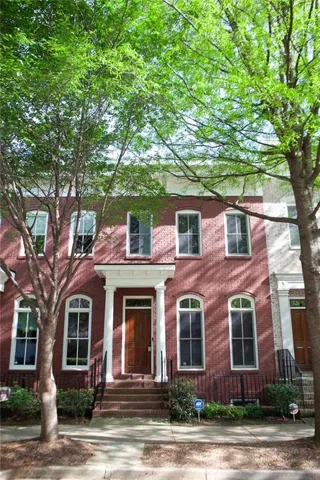Brick facade featuring a columned portico, a solid wood entry door, and arched lower-level windows