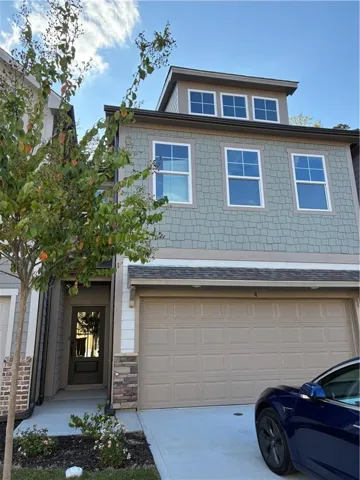 Contemporary exterior with patterned siding, stone veneer accents, and a panel-style garage door