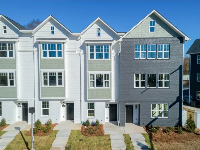 Contemporary townhome facade featuring white brick, gray brick, and shingle siding accents