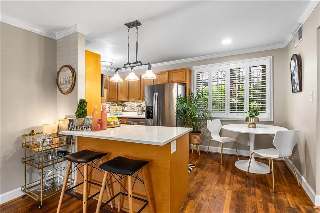Kitchen featuring stainless steel fridge with ice dispenser, brown cabinets, dark wood-style floors, a kitchen bar, and baseboards